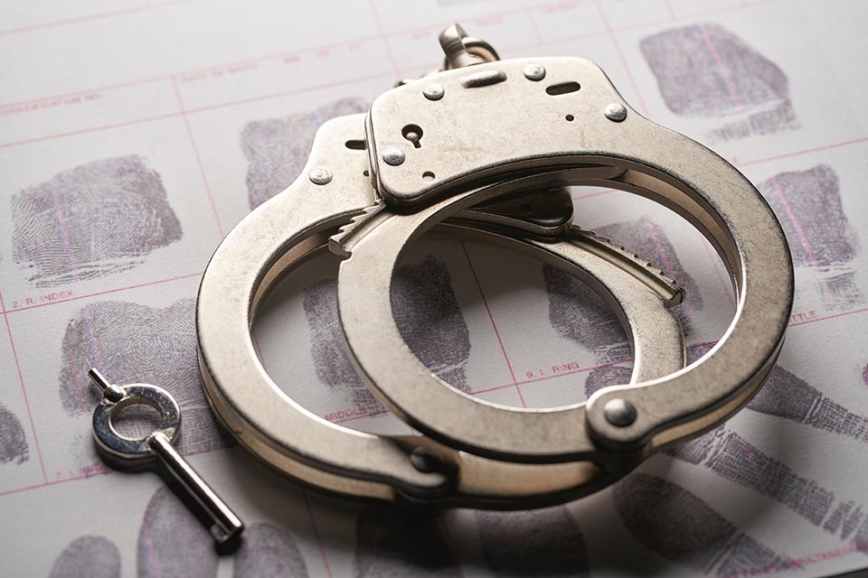 Handcuffs for a criminal on top of a fingerprint sheet
